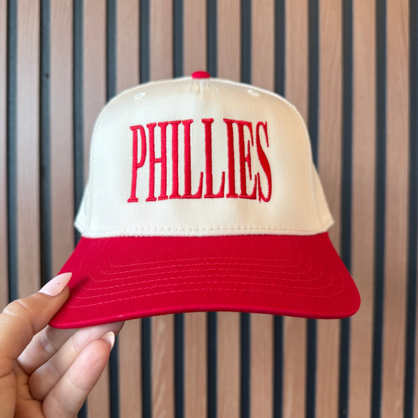 Cap with 'Philadelphia' text held by a hand against a striped background