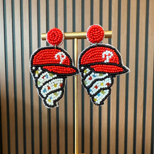 Pair of beaded earrings on a wooden stand with striped background