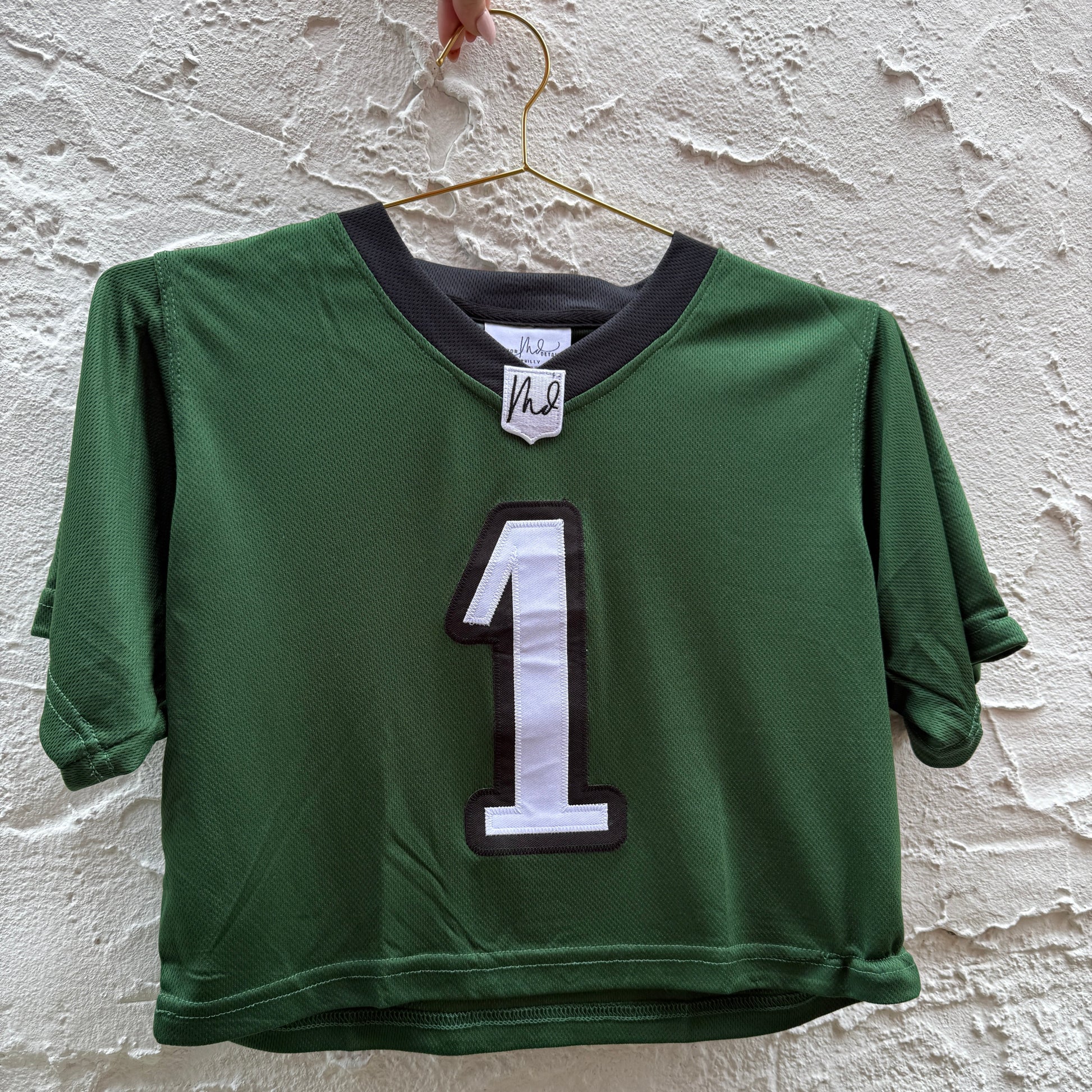 Green sports jersey with number 1 on a textured white background