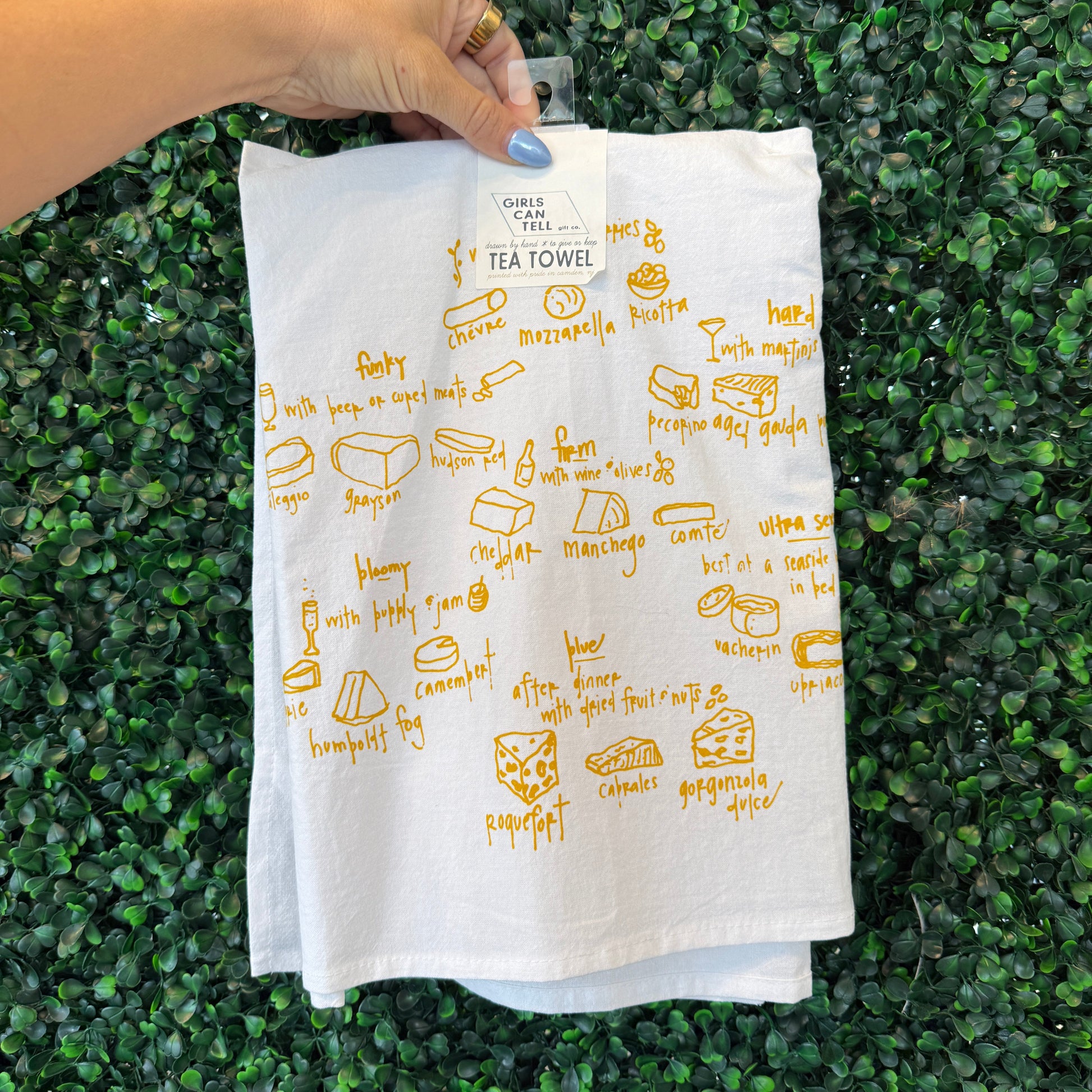 Hand holding a white cloth with yellow text and graphics on a green grass background