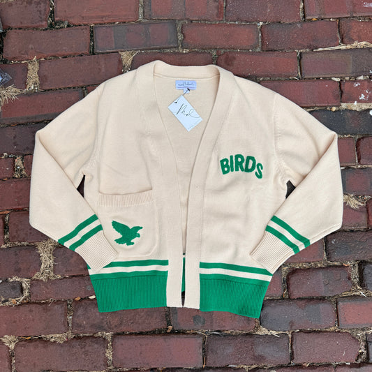 Cardigan with 'Birds' text and green accents on a brick wall