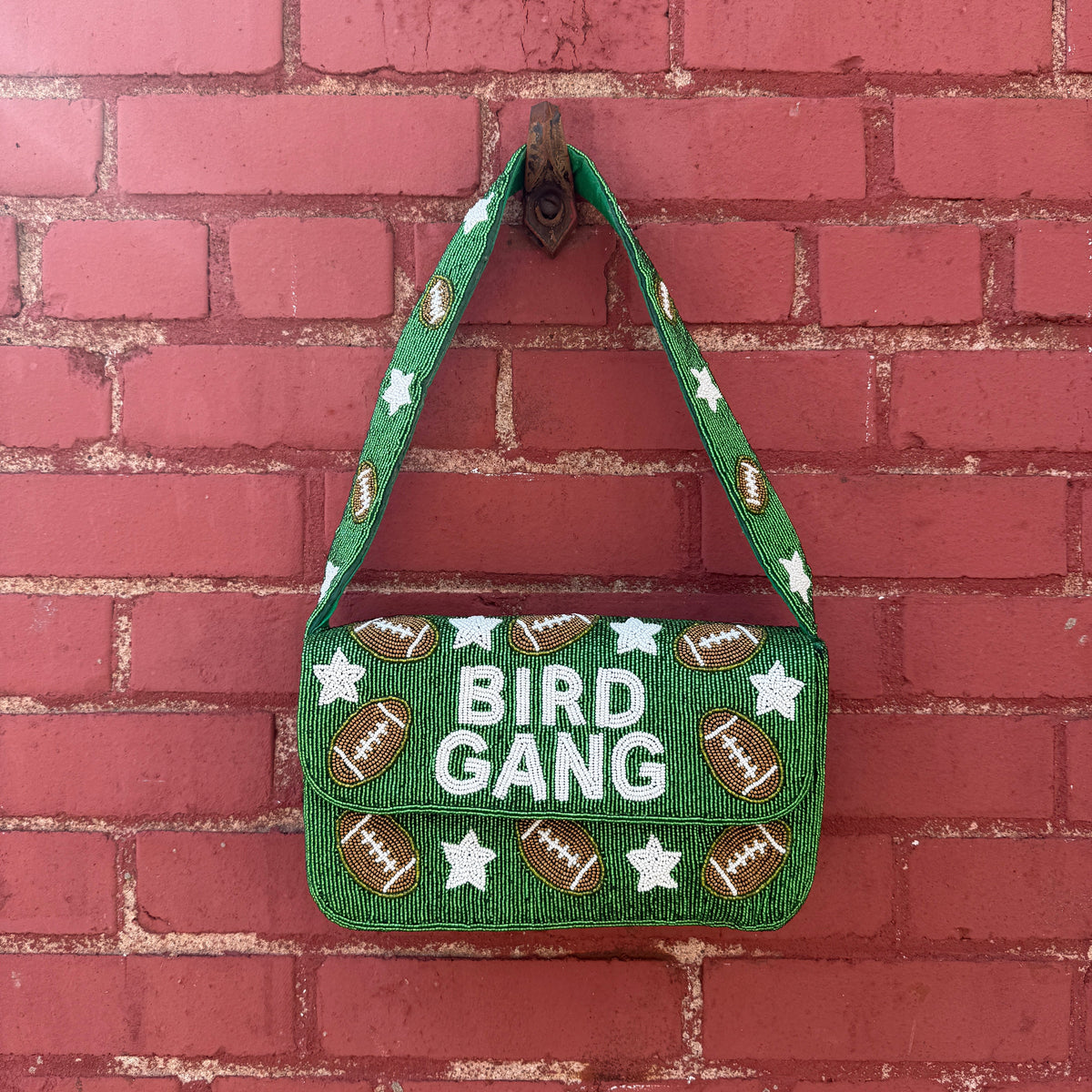 Green bag with 'Bird Gang' text and football designs on a red brick background