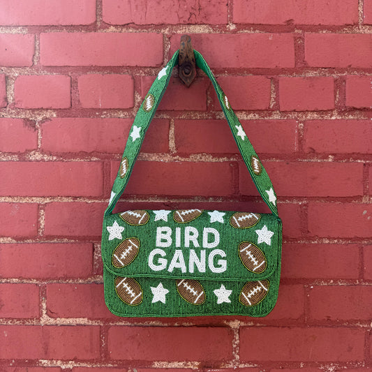 Green bag with 'Bird Gang' text and football designs on a red brick background