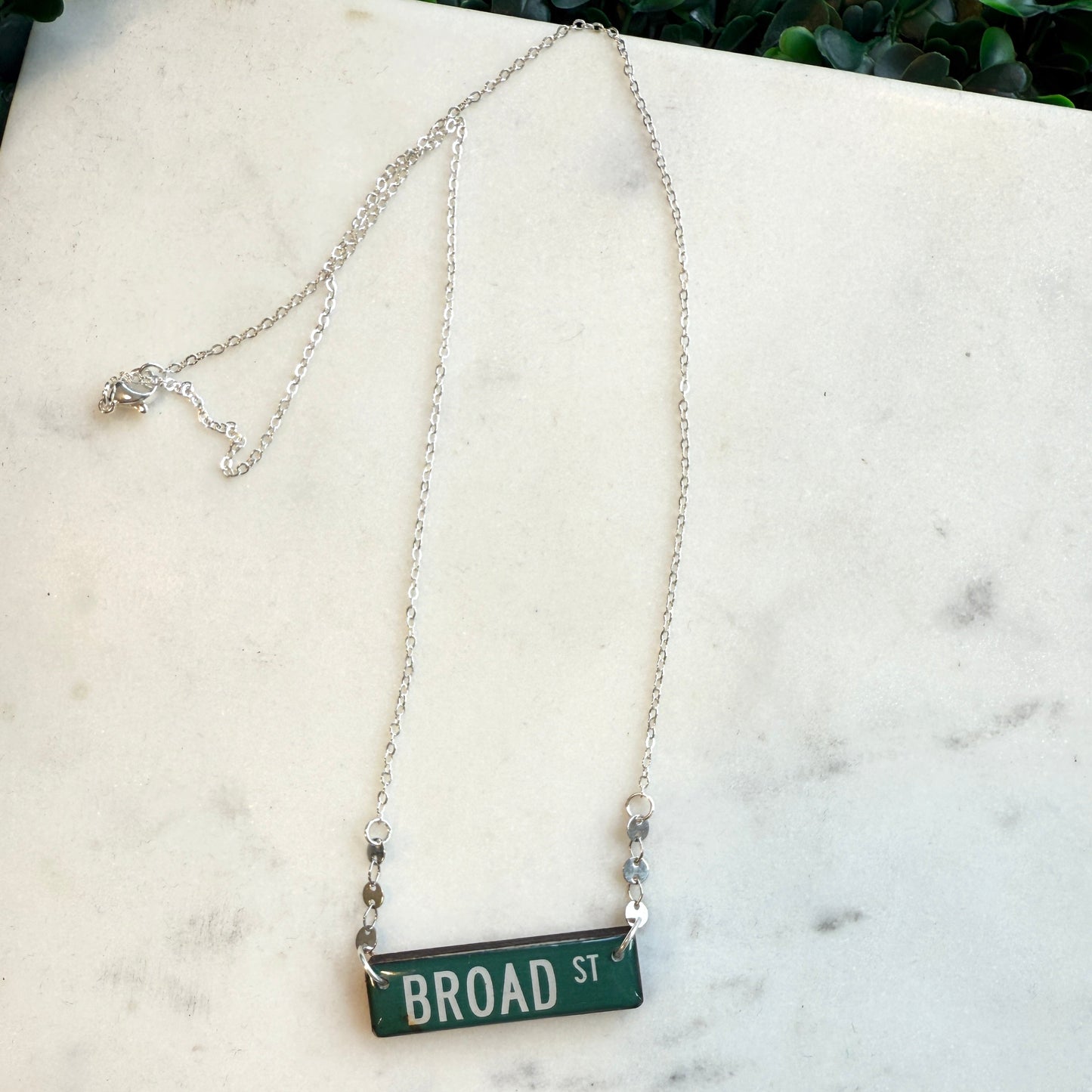 Necklace with a 'BROAD ST' pendant on a marble surface